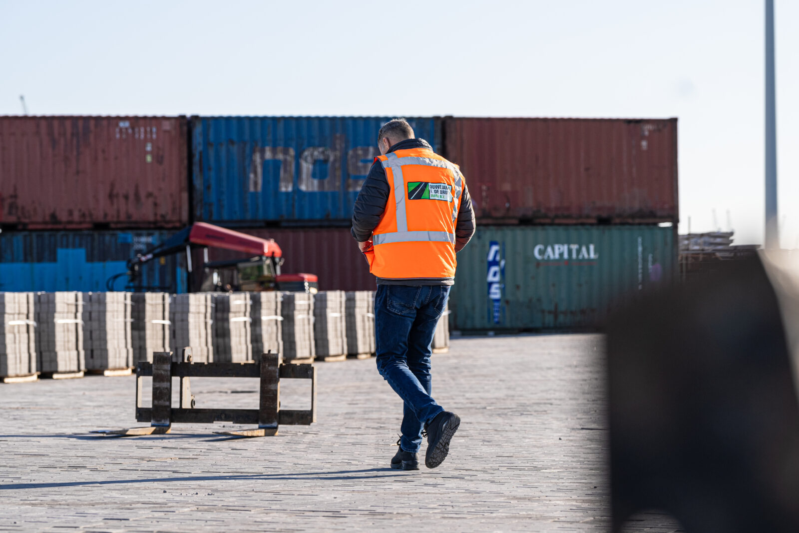 Medewerker van Ouwejan & F. de Bruijn inspecteert de voortgang van een bestratingsproject op locatie.