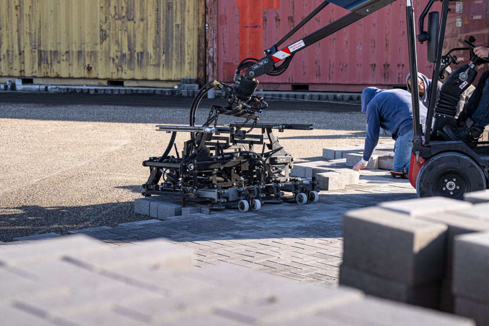 Machinale aanleg van bestrating op een projectlocatie met een bestratingsmachine.