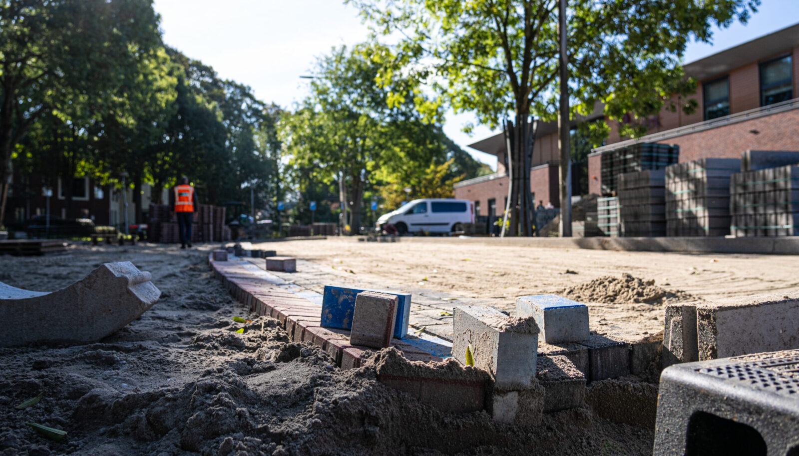 Herinrichting van een straat met nieuwe bestrating en voorbereidend grondwerk in een woonwijk.