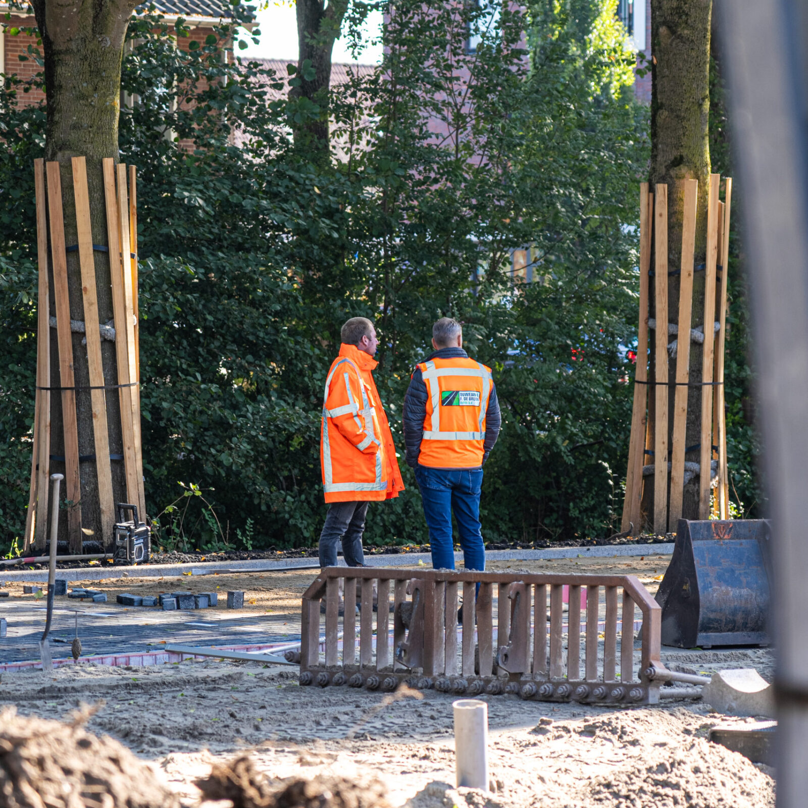 Twee medewerkers van Ouwejan & F. de Bruijn bespreken de voortgang van een terreinproject op locatie.