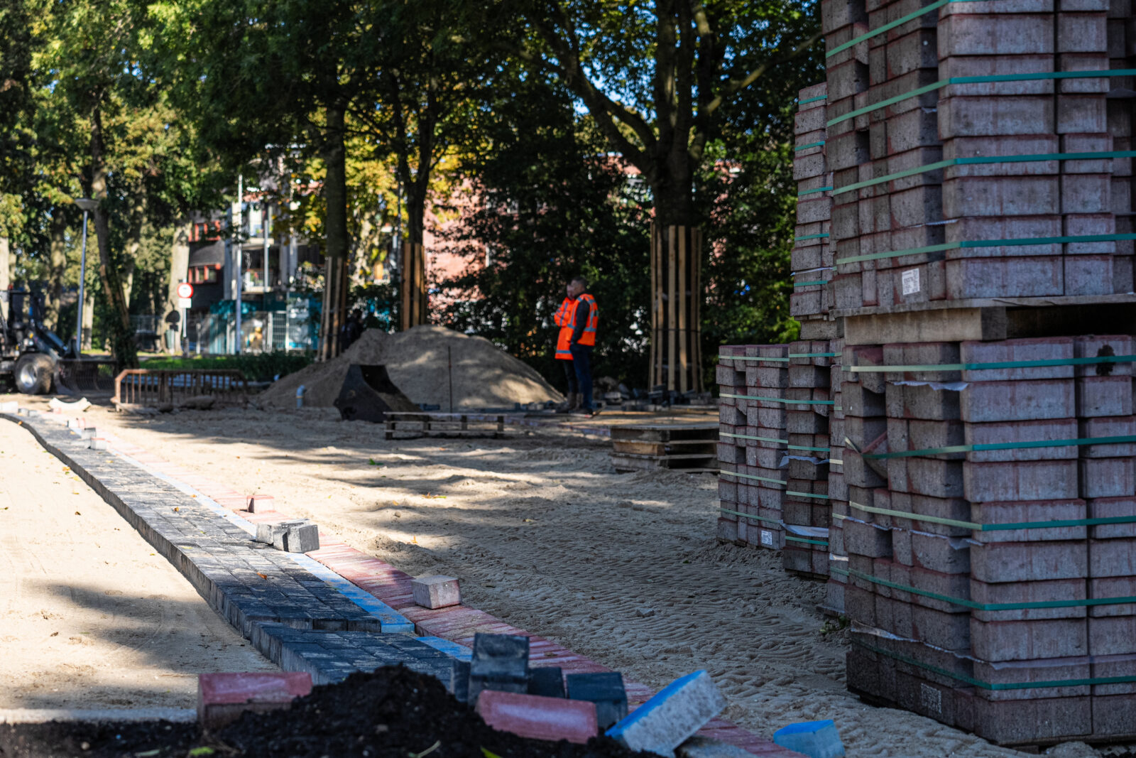 Werkzaamheden aan een straat met nieuwe bestrating en opgeslagen materialen voor de volgende fase van het project.