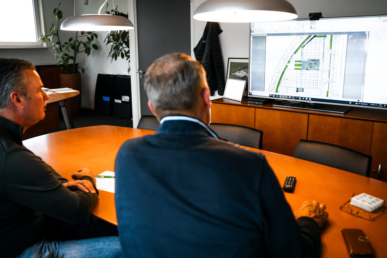 Medewerkers bespreken een terreinproject aan de hand van een digitale projecttekening.